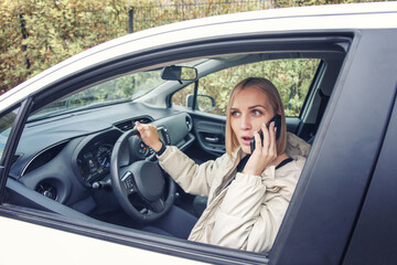 a girl with a surprised face speaks on the phone while driving a car