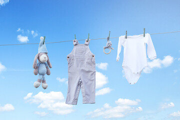 baby clothes drying on a rope against blue clouds