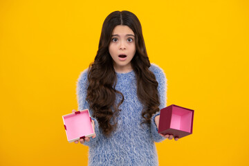 Child with gift present box on isolated studio background. Gifting for kids birthday. Unhappy sad teenager girl.