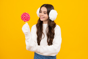 Teen girl hold lollipop caramel on yellow background, candy shop. Teenager with sweets suckers. Happy face, positive and smiling emotions of teenager girl.