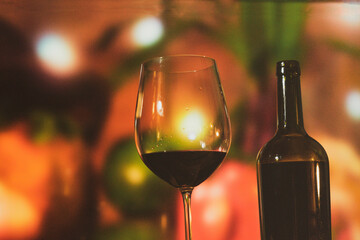 a crystal glass with wine on some stones and a bottle of wine on a trunk table with colored lights and glamor to share a pleasant moment with a lot of flavor and pleasure
