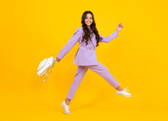Fototapeta na wymiar Schoolgirl in school uniform with school bag. Schoolchild, teen student hold backpack on yellow isolated background. Run and jump. Happy face, positive and smiling emotions of teenager girl.