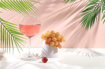 Modern still life with white wine, alcoholic cocktail and grapes on pastel background with long...