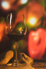 a crystal glass with wine on some stones and a bottle of wine on a trunk table with colored lights and glamor to share a pleasant moment with a lot of flavor and pleasure