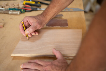 Carpenter drawing on wood craft at workshop to produce furniture. Professional tools for crafting. DIY maker and carpentry work concept.