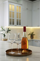 Bottle and glasses on white marble table in kitchen. Luxury interior