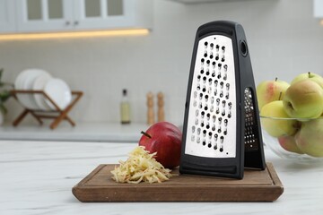 Grater and fresh ripe apples on white table in kitchen. Space for text