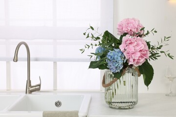 Beautiful hortensia flowers in vase on kitchen counter. Space for text