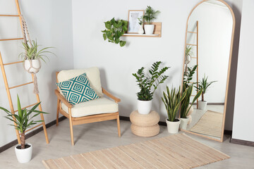 Stylish living room interior with wooden furniture, houseplants and full length mirror near white wall