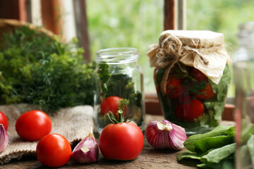 Glass jars, fresh vegetables and herbs on wooden table indoors. Pickling recipe