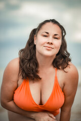 Fototapeta na wymiar beautiful woman 40 years old on the beach in plus size swimsuit