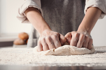 Obraz na płótnie Canvas Woman kneading dough at table in kitchen, closeup