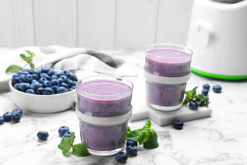 Tasty blueberry smoothie with mint and fresh berries on white marble table. Space for text