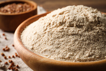Bowl of buckwheat flour on wooden table, closeup