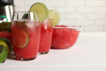 Tasty watermelon drink with lime and ingredients on white table, space for text