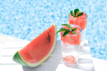Refreshing drink in glasses and sliced watermelon near swimming pool outdoors