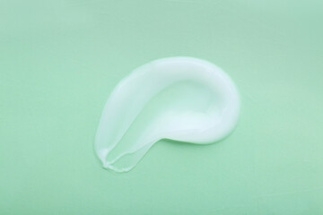Sample of body cream on turquoise background, top view