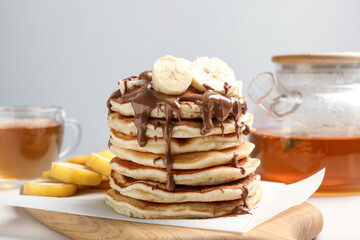 Tasty pancakes with sliced banana served on white table