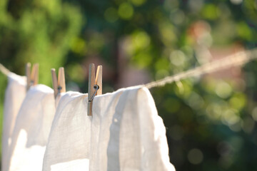 Washing line with drying shirt against blurred background, focus on clothespin