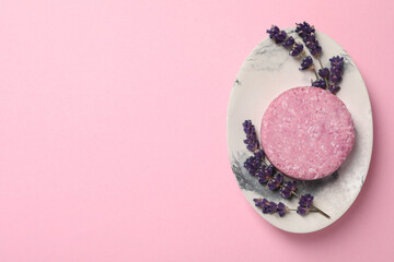 Solid shampoo bar and lavender flowers on pink background, top view. Space for text