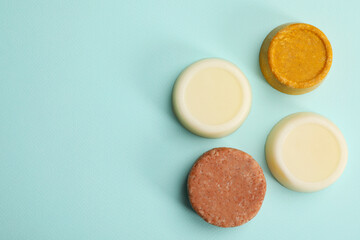 Group of solid shampoo bars on turquoise background, flat lay. Space for text