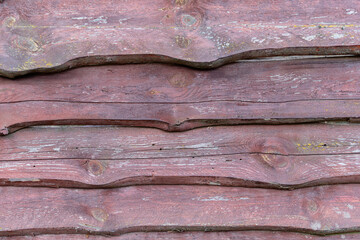 Fence made of rough old wooden boards with peeling dark brown paint. Horizontal arrangement
