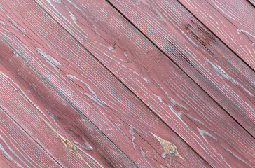 Fence made of rough old wooden boards with peeling dark brown paint. Diagonal arrangement