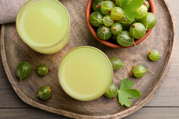 Tasty gooseberry juice and fresh berries on wooden table, flat lay