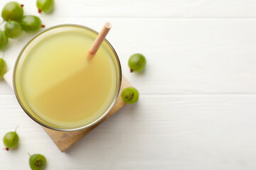 Tasty gooseberry juice on white wooden table, flat lay. Space for text