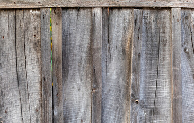 Fence made of rough old unpainted wooden boards. Vertical arrangement