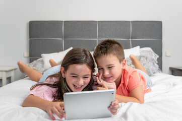 Cute little children with digital tablet using internet at home. Caucasian little sister and...