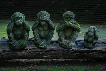 Three monkeys and son statues sitting on a log meaning of ignoring bad things that will affect the...