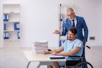 Obraz premium Young male employee in wheel-chair feeling bad at workplace