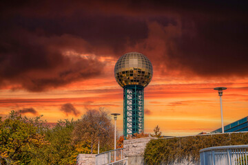 a gorgeous view of the gold and green Sunsphere surrounded by lush green trees with powerful clouds at sunset in Knoxville Tennessee USA - obrazy, fototapety, plakaty