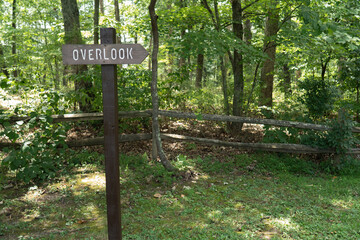 Wooden arrow sign that reads overlook and points to the right, set on a wooden post in the grass...