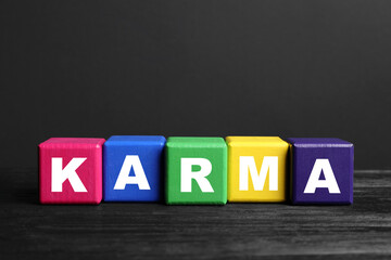 Fototapeta na wymiar Word Karma made of colorful cubes with letters on black wooden table