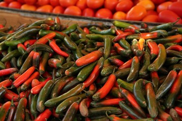 Heap of fresh Serrano peppers on counter at market, closeup