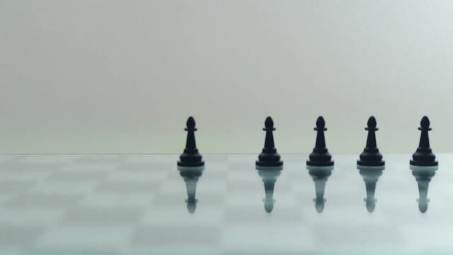 Stop-motion of chess pieces moving around a reflective chess board.