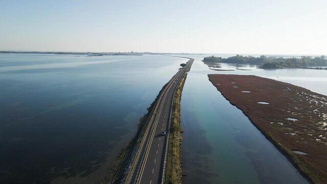 Aerial view of vehicles driving on a beautiful road crossing the lagoon in Grado near Gorizia, Friuli Venezia Giulia, Italy.