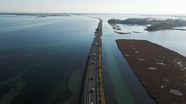 Aerial view of vehicles driving on a beautiful road crossing the lagoon in Grado near Gorizia, Friuli Venezia Giulia, Italy.