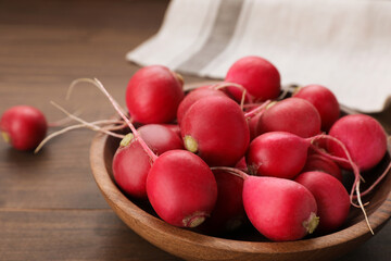 Bowl with fresh ripe radishes on wooden table, closeup