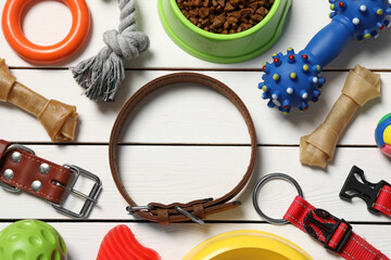 Flat lay composition with dog collar, toys and food on white wooden table