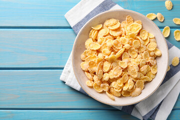 Tasty crispy corn flakes on light blue wooden table, flat lay. Space for text