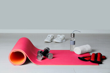 Exercise mat and other sport equipment on light wooden floor indoors