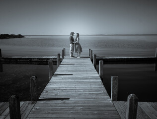 a young couple embrace on a long wooden pier