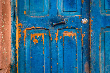 Old wooden blue painted and textured door, with rusty metal hinge