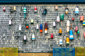 Traditional vintage lobster buoys hanging on a shingled wall. - obrazy, fototapety, plakaty