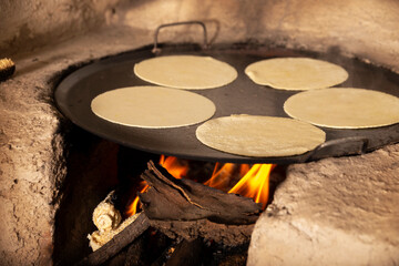 Handmade corn tortillas cooked in a traditional rustic wood stove called "fogon", type of cooking common in rural communities in Mexico and other countries.
