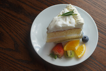 Coconut cake and half strawberry, kiwi slices, two orange slices, one blueberry on a white plate, on a wooden table, dessert, food, nature, copy space