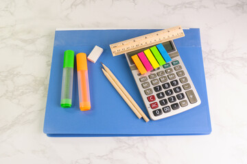 blue folder and writing equipment with Calculator, highlighter, pencil, ruler, eraser on the white table at the office